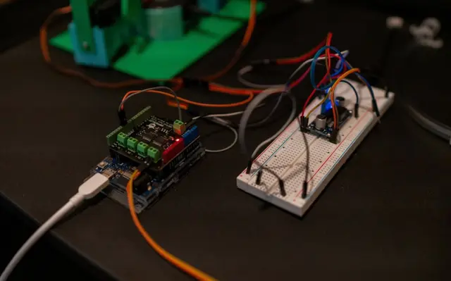 Arduino Uno with DFRobot Quad Motor Driver Shield and breadboard wiring harness — bench assembly